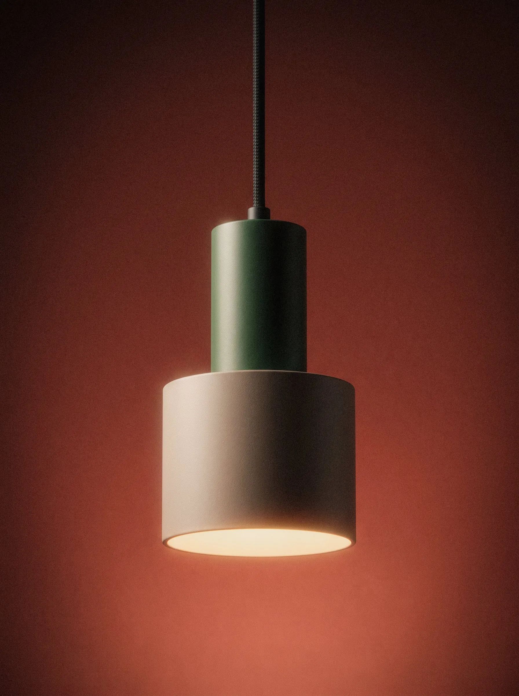 Pendant light with a green top and a pink shade against a red wall